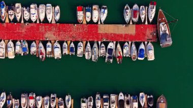 Deniz yeşili deniz manzarasında çeşitli teknelerle çevrili birkaç rıhtım. İHA görüntüleri gündüz marinada..