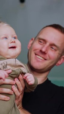 Küçük çocuklarıyla oynayan pozitif beyaz ebeveynler. Anne, tatlı bebeğini yanağından öpüyor. Düşük açı. Dikey video