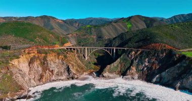 Bixby Creek Köprüsü 'nün kıyı kanyonu üzerindeki hava manzarası. Bixby Creek Köprüsü kumlu bir sahil ve Pasifik okyanusunun yanındaki vadiyi kaplıyor..