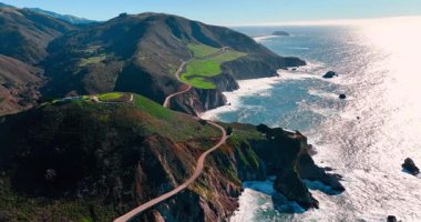 Güneş ışığı, dolambaçlı sahil yolu yakınlarındaki okyanus suyuna yansıyor. Big Sur 'daki 1. Otoyol ve Pasifik kıyı şeridi yüksek açılı..