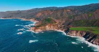 Big Sur kıyı şeridi ve köprüsünün geniş panoramik hava manzarası. Kaliforniya Pasifik kıyısındaki engebeli mavi sularla Bixby Köprüsü 'nün uzak manzarası.
