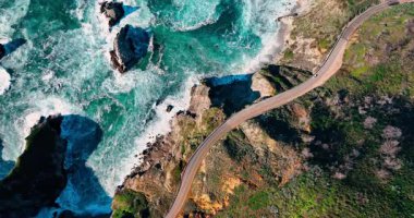 Birinci otoyol kavisi ve okyanus taşlarının en alt perspektifi. Büyük Sur 'da kayalık kıyı şeridi ve turkuaz Pasifik Okyanusu' nun yanında yüksek açılı bir hava manzarası..