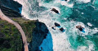 Dik sahil uçurumundaki 1. karayolu kavşağının üst görüntüsü. Big Sur 'da kayalık kayalıklara ve turkuaz Pasifik Okyanusu sörfüne bakan kıyı şeridi manzarası..