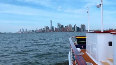 Tekne güvertesinden New York 'un ufuk çizgisi görünüyor. Teknenin ahşap güvertesinden Manhattan 'ın finans bölgesine doğru bakan su manzarası.