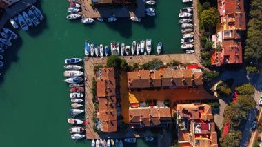 Marina rıhtımlarının ve yerleşim yerlerinin havadan görüntüsü. İspanya 'da dar bir kanala demirlemiş terracotta kiremitli çatılar, palmiye ağaçları ve yatlar..