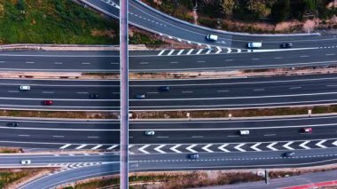 Pedestrian walkway over motorway lanes. Narrow pedestrian bridge crossing a wide multi-lane highway with traffic and road markings.