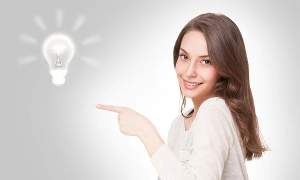 Young brunette beauty with light bulb symbol. — Stock Photo, Image