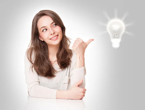 Young brunette beauty with light bulb symbol. Stock Picture