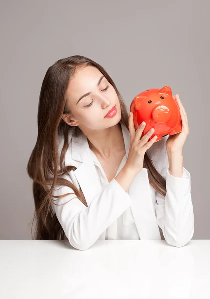 Brunette beauty with orange piggy bank. — Stock Photo, Image