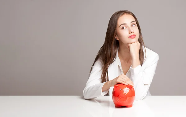 Brünette Schönheit mit orangefarbenem Sparschwein. — Stockfoto