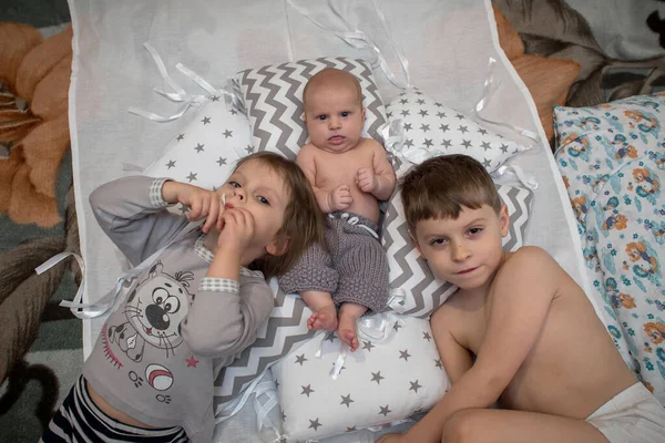 Bruder Und Schwester Liegen Mit Dem Baby Zwischen Den Kissen — Stockfoto