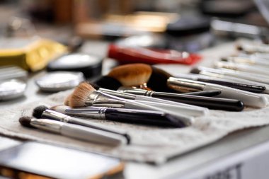 Kozmetik fırçalar, boyalar, masanın üzerindeki gölgeler.