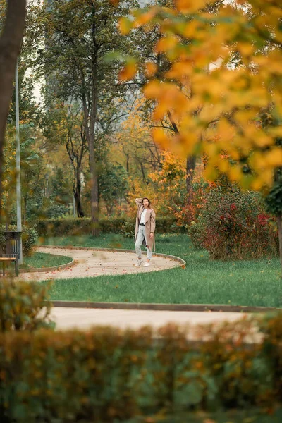 Белая Девушка Розовом Пальто Синих Джинсах Дырками Танцует Осеннем Парке — стоковое фото