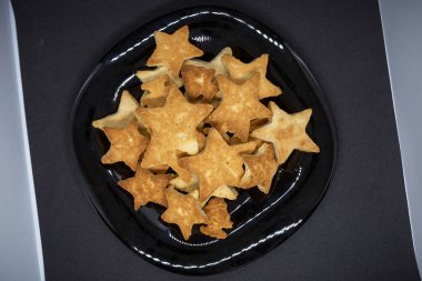 Yıldız şeklinde korkunç bir ev yapımı kurabiye siyah bir tabakta yatar. Yakın plan.