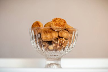 Ev yapımı kurabiyeler ve cevizler bir kasede ve beyaz bir masada. Yakın plan.