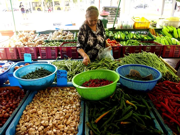 A woman picks fresh vegetable from a market in the town of Tampines in Singapore — Stock Photo, Image