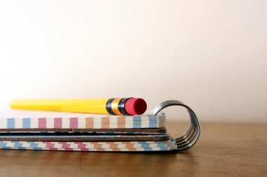 Renkli küçük spiral defter ve bir kalem ahşap bir masa üzerinde