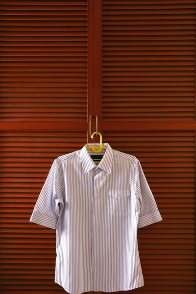 Polo shirt hanging by a clothes cabinet door — Stock Photo, Image