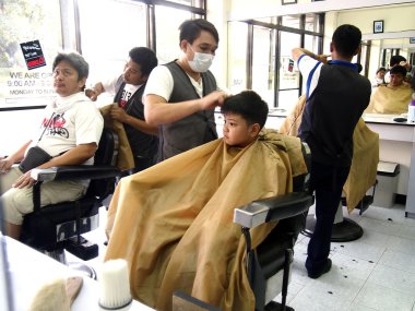 Young boy gets a haircut at a barber shop clipart