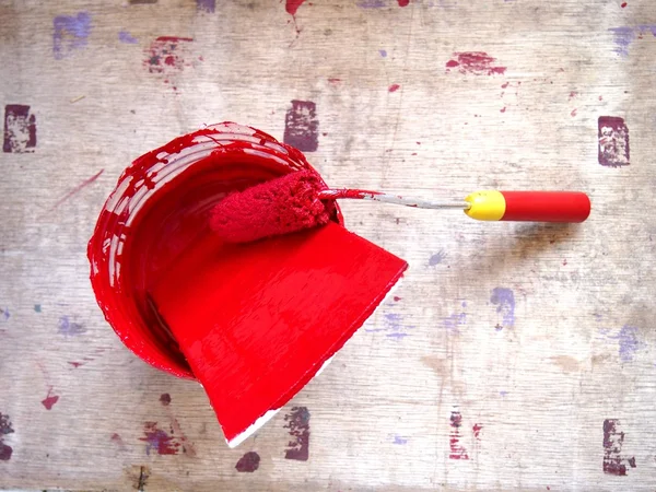 Can and roller brush with red paint — Stock Photo, Image