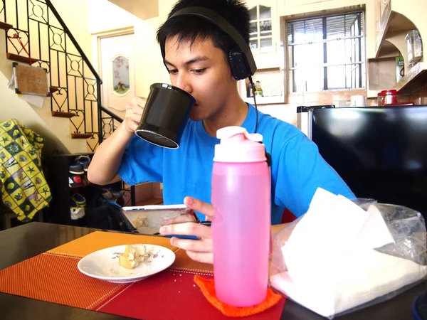 Jovem adolescente fazendo um lanche enquanto assiste em um dispositivo móvel — Fotografia de Stock