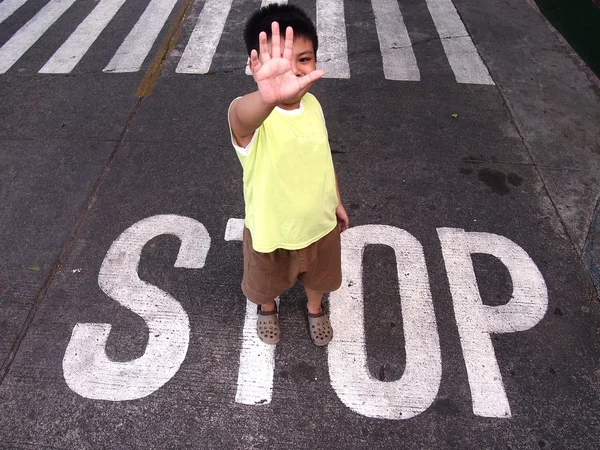 若い男の子が歩行者レーンの横にある「停止」単語を立っている間一時停止標識を作る — ストック写真