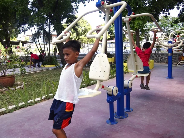 Les jeunes enfants jouent dans un parc extérieur avec des équipements de gymnastique — Photo