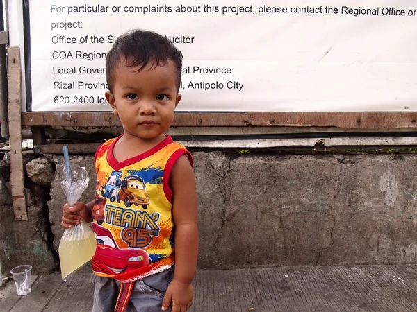 Un jeune garçon porte une boisson gazeuse dans un sac en plastique avec de la paille . — Photo