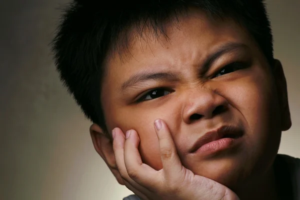 Mladý chlapec odpočívá jeho tvář s hloupým výrazem na ruce — Stock fotografie