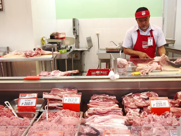 Un carnicero en una sección de carne de una tienda de comestibles —  Fotos de Stock