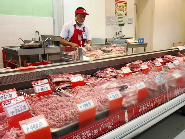 Un carnicero en una sección de carne de una tienda de comestibles —  Fotos de Stock