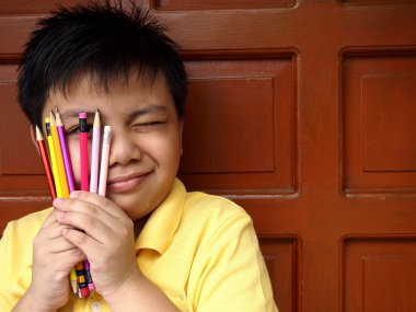 Genç çocuk bir grup renkli kalemler yüzüne holding