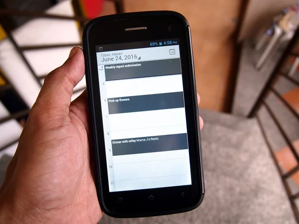 Hand holding a smartphone with three calendar reminders