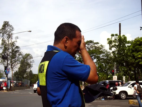 A traffic enforcer wipes his sweat as he stands under the heat of the sun at a road intersection — Stock Photo, Image