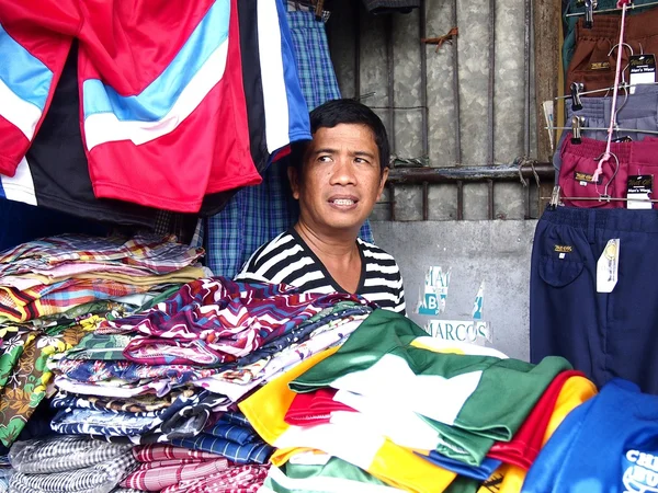 Bir adam çeşitli renkli gömlek ve pantolon satıyor — Stok fotoğraf