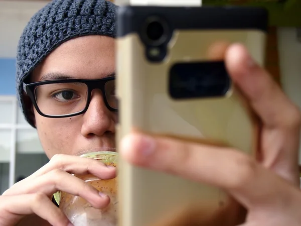 Teenager wearing a bonnet and eyeglasses using a smartphone — Stock Photo, Image