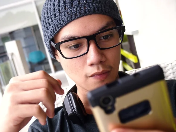 Adolescent portant un bonnet et des lunettes à l'aide d'un smartphone — Photo