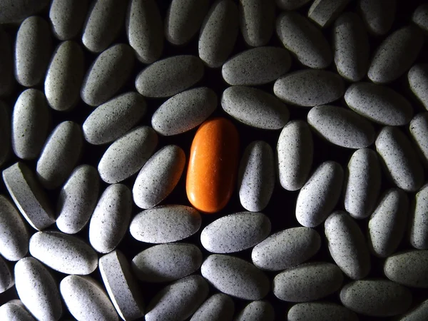 Píldora de color naranja entre píldoras blancas —  Fotos de Stock