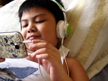 Genç, çocuk akıllı telefon ve kulaklık ile