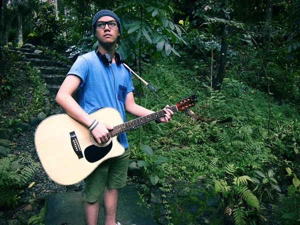 Tiener houdt van een gitaar op een natuurpark — Stockfoto