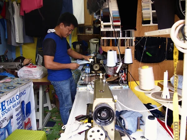 Een kleermaker werkt op een jurk binnen een spastische winkel. — Stockfoto