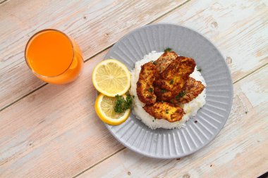 Taze pişirilmiş ballı hardallı tavuk göğsü pilav ve portakal suyu ile servis edilir..