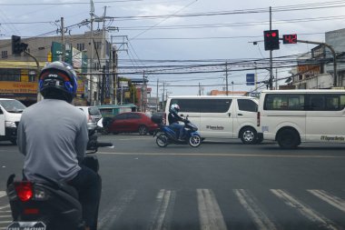 Cainta, Rizal, Filipinler - 18 Mayıs 2021: Motosiklet sürücüsü kavşakta duruyor ve trafik lambasının yeşile dönmesini bekliyor.