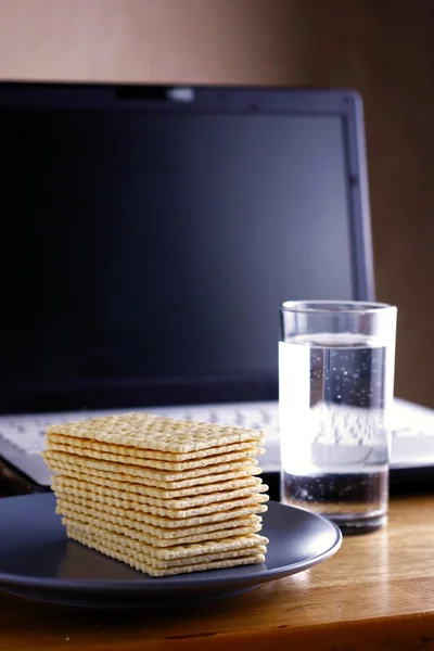 Soda Crackers, Glass of water and a computer — Stock Photo, Image