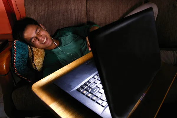 Asian teen laughing and watching video on a laptop — Stock Photo, Image