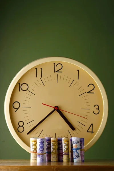 Une horloge analogique et des rouleaux de papier-monnaie — Photo