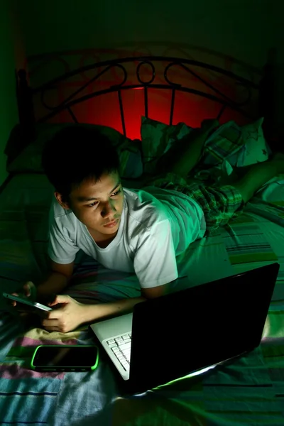 Young Teen in front of a laptop computer and on a bed and using a tablet — Stock Photo, Image