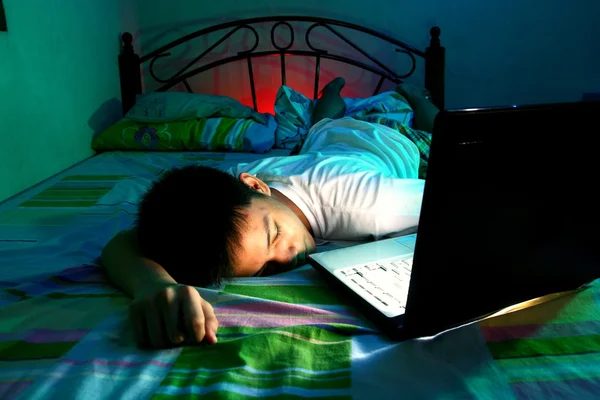 Young Teen sleeping front of a laptop computer and on a bed