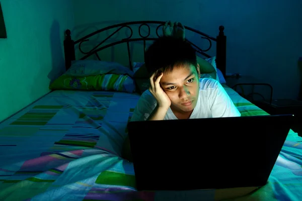 Young Teen in front of a laptop computer and on a bed — Stock Photo, Image