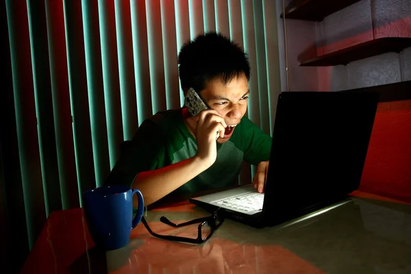 Adolescente joven usando un teléfono celular o teléfono inteligente frente a una computadora portátil — Foto de Stock